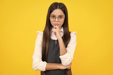 Serious teenager girl. Emotional portrait of caucasian teenager child girl isolated on studio yellow background