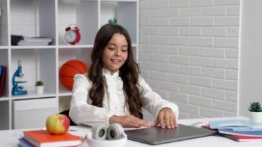 happy child starting school online lesson with laptop wearing headphones, communication technology.