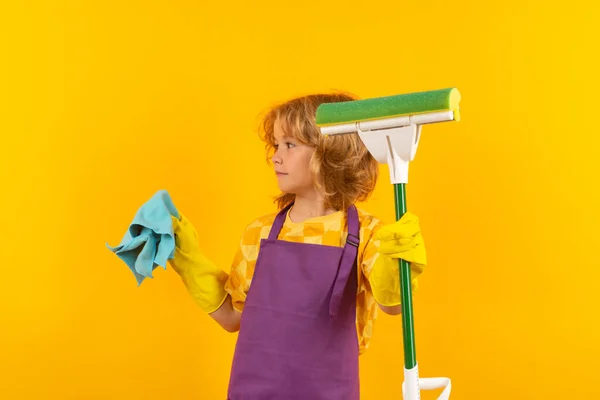 Housekeeping, home chores. Children helping with housekeeping, cleaning the house. Housekeeping at home. Cute child boy helping with housekeeping on yellow studio backdround