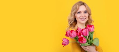 glad young woman with spring tulip flowers on yellow background. Woman isolated face portrait, banner with mock up copy space