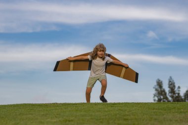 Childhood dream imagination concept. Kid playing with toy airplane and dreaming future. Happy boy pilot play with airplane outdoors