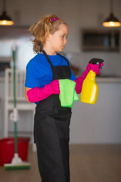 Portrait of child cleaning, concept growth, development, family relationships. Housekeeping and home cleaning concept. Child use duster and gloves for cleaning. Home kitchen background