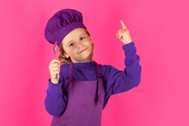 Funny kid chef cook with spoon. Child in cook uniform. Chef kid isolated on pink background. Cute child to be a chef. Child dressed as a chef hat