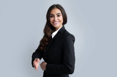 Takım elbiseli bir iş kadını gülümseyerek selamlama ve hoş geldin demek için tokalaşıyor. Başarılı bir iş. İş kadını tokalaşıyor. Dostça bir selamlama ve karşılama olarak el sıkışalım.