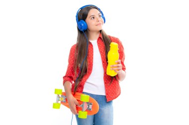 Stüdyoda su şişesi ve kulaklığı olan genç bir kız. Bahar liseli kız trendi, şehirli genç tarzı.