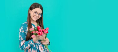 glad child in glasses with tulips. mothers or womens day. kid hold flowers for 8 of march. Banner of spring child girl with tulips flowers bouquet, studio portrait with copy space