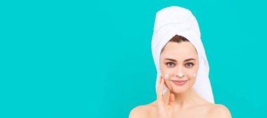 smiling young lady apply face cream on blue background. Beautiful woman isolated face portrait, banner with mock up copy space