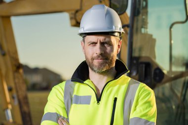 Worker with bulldozer on site construction. Man excavator worker. Construction driver worker with excavator on the background. Construction worker with tractor or construction vehicle at building