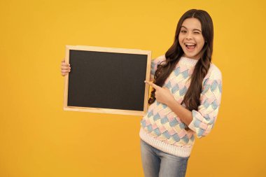Okul satış kurulu. Neşeli genç kız, sarı arka planda fotokopi alanı olan karatahta tutuyor. Heyecanlı bir yüz. Şaşırtıcı bir ifade, neşeli ve mutlu.