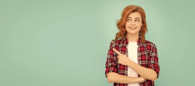 Mavi arka planı gösteren kareli tişörtlü kızıl saçlı mutlu bir kadın. İzole edilmiş yüz portresi, kopyalama alanı oluşturulmuş pankart