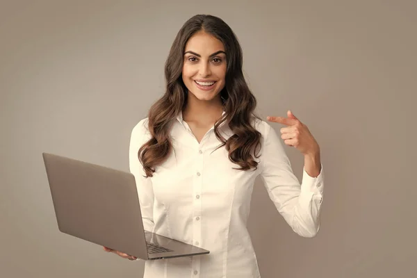 stock image Portrait of a cheerful young casual girl standing isolated over gray background, using laptop computer. Business woman at work