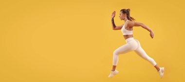 active sport girl runner running on yellow background. Woman jumping running banner with mock up copyspace