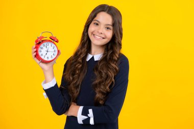 Öğrenci kız saati sarı arka planda izole edilmiş. Okula gitme vakti. Alarmlı saati olan genç bir çocuk, uyanma zamanını gösteriyor.