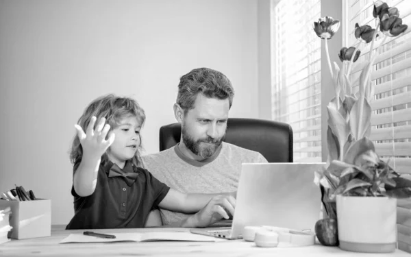 bearded dad or school private tutor teaching boy son with modern laptop, e-learning.