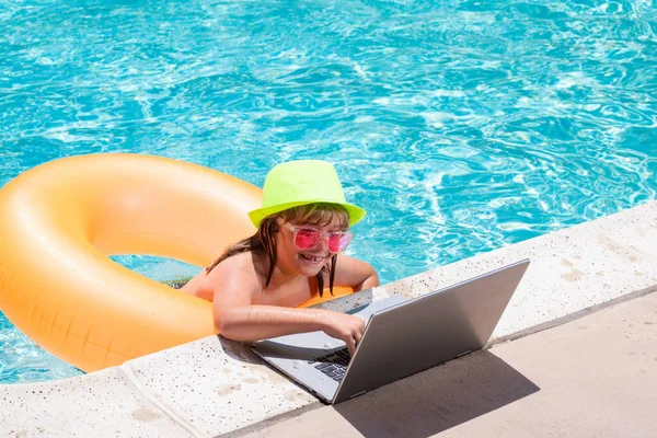 夏天的生意儿童遥控器在游泳池里的笔记本电脑上工作 小商人在网上工作的笔记本电脑夏天游泳池的水 在热带海滩工作的小商人 — 图库照片