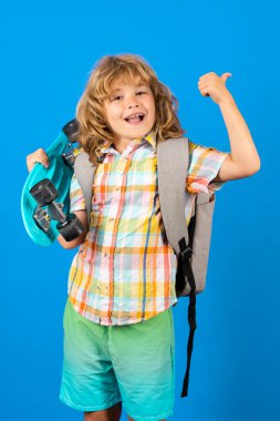 Happy child boy holding skateboard over blue background isolated. Studio portrait of fashion kids