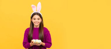 Komik tavşan kulaklı mutlu Paskalya kızı bıldırcın yumurtası tutuyor. Paskalya çocuğu yatay posteri. Tavşan çocuğun web afişi, kopyalama alanı