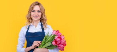 glad girl in apron with spring tulip flowers on yellow background. Woman isolated face portrait, banner with mock up copy space