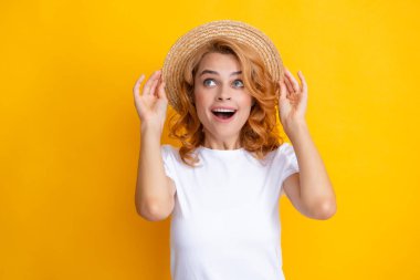 Expressive girl with surprised face. Young redhead woman in straw hat, surprised expression, isolated on yellow background. Summer lifestyle studio portrait