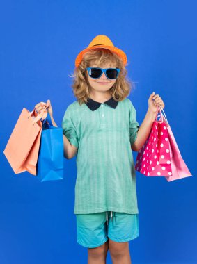Fashion child on shopping. Portrait of a kid with shopping bags. Happy boy holding shopping bags. Studio portrait