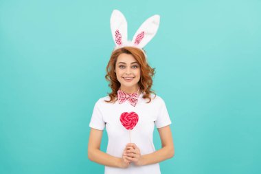 glad easter woman wear bunny ears hold heart lollipop.