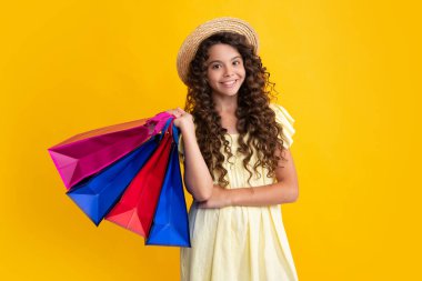 Beautiful fashion teenager child girl with shopping bags on yellow background. Shopaholic shopping and fashion. Kid with shopping sale bags. Happy teenager, positive and smiling emotions