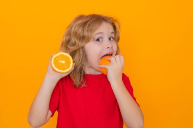 Kid with orange in studio. Studio portrait of cute child hold orange isolated on yellow background