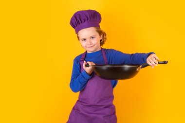 Kid boy chef cook with cooking pan. Chef kid boy making healthy food. Portrait of little child in chef hat isolated on studio background. Child chef. Cooking process