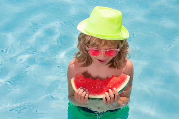 Children with watermelon playing in swimming pool. Kids holidays and summer vacation concept