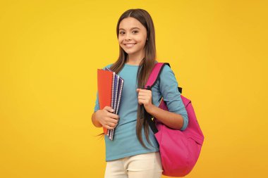 Schoolchild, teenage student girl hold book on yellow isolated studio background. School and education concept. Back to school. Happy teenager portrait. Smiling girl