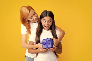 Young teen girl giving gift box to her mother on color background. Happy family. Mother and daughter with present gift