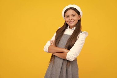 Happy girl face, positive and smiling emotions. Portrait of caucasian teen girl with arms folded, isolated on yellow background. Cute teenager child