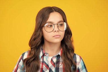 Sarı stüdyo arka planında güzel, ciddi bir genç kızın portresi.