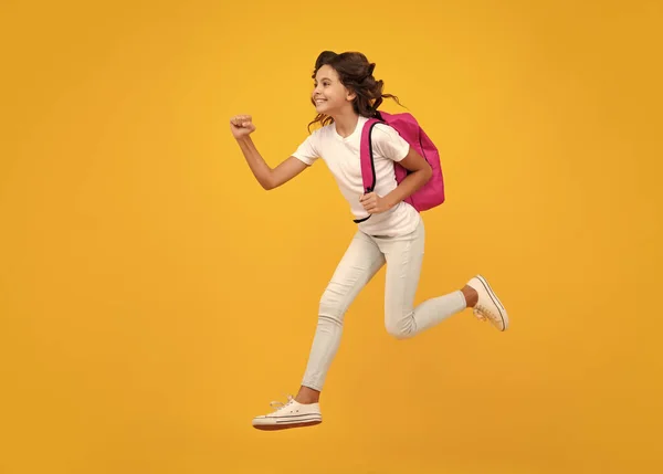 Amazed teen girl. Back to school. Teenage school girl ready to learn. School children on yellow isolated background. Run and jump. Excited expression, cheerful and glad