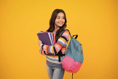 School girl hold copybook and book on yellow isolated studio background. School and education concept. Teenager girl in school uniform. Happy teenager, positive and smiling emotions of teen girl