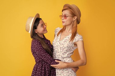 Sarı arka planda hasır şapkalı neşeli anne ve çocuk.