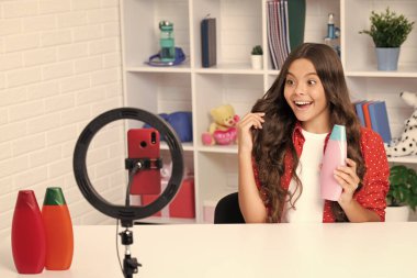 Teenager child recording video tutorial for social media with smart phone. Influencer teenager creating new content for blog while streaming online. Excited face, cheerful emotions of teenager girl