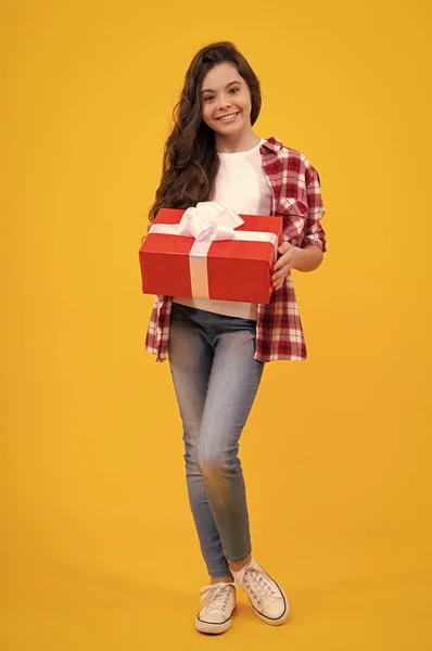 stock image Happy teenager, positive and smiling emotions of child girl. Teenager kid with present box on isolated yellow background. Teen girl giving birthday gift. Present, greeting and gifting concept