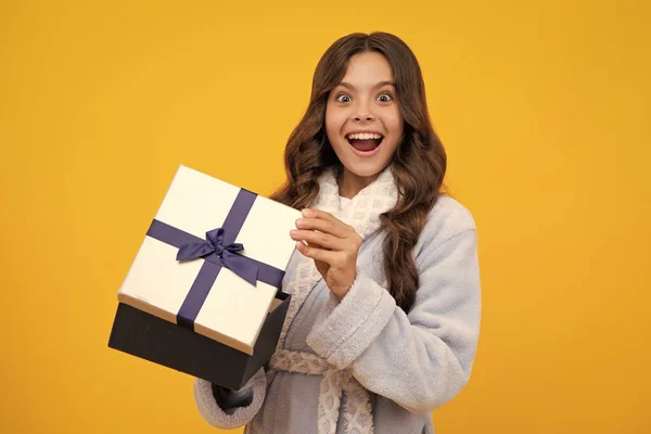 stock image Amazed teen girl. Teenager child holding gift box on yellow isolated background. Gift for kids birthday. Christmas or New Year present box. Excited expression, cheerful and glad