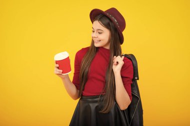 Bir fincan cappuccino kahvesi ya da çayı götüren genç kız. Sarı arka planda yemek fincanı olan çocuk, sabah içeceği. Mutlu ergen portresi. Gülümseyen kız