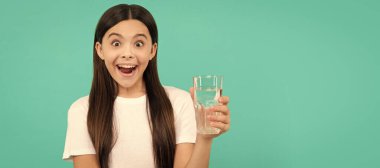 surprised girl drink glass of water to stay hydrated and keep daily water balance, drink water. Banner of child girl with glass of water, studio portrait with copy space