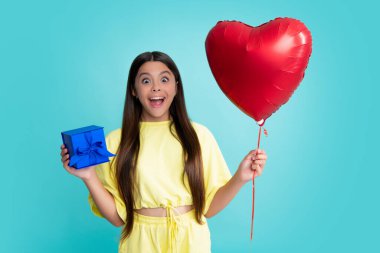 Child with gift present box on isolated studio background. Gifting for kids birthday. Excited face, cheerful emotions of teenager girl