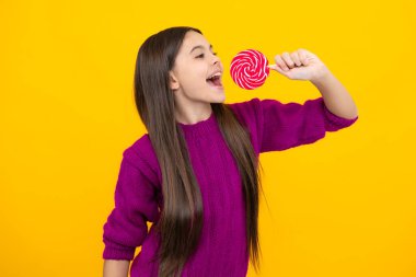 Sarı izole edilmiş arka planda lolipopu olan havalı bir genç çocuk. Tatlı çocukluk hayatı. Lezzetli lolipop şekerli genç kız