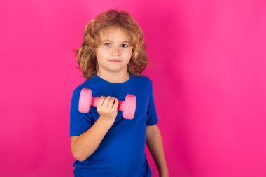 Sportif çocuklar, stüdyo portresi. Dambıl kaldıran çocuk. Dambılı şirin çocuk eğitimi. Çocuk fitness. Çocuk, dambıllarla egzersiz yapıyor. Sağlıklı çocuklar