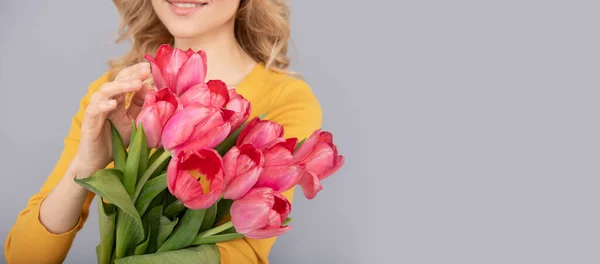 cropped woman with tulips. lady hold flowers for spring holiday. girl with bouquet on grey background. floral present for womens day. 8 march and mothers day. copy space.