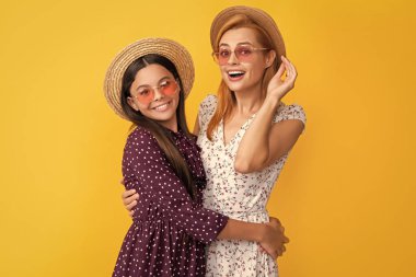 Sarı arka planda hasır şapkalı mutlu anne ve kız..