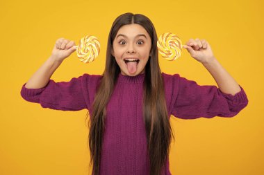 Heyecanlı bir yüz. Genç kız sarı arka planda lolipop karamel tutuyor, şekerci dükkanı. Tatlılı ergen enayiler. Şaşırtıcı bir ifade, neşeli ve mutlu.
