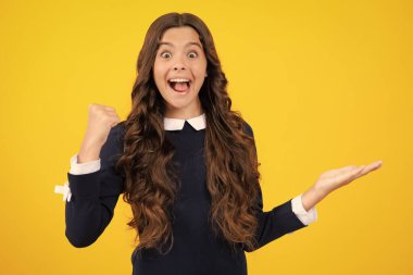 Wow, its unbelievable. Shocked teenager child pointing aside at copy space. Teen girl pointing with two hands and fingers to the side. Excited face. Amazed expression, cheerful and glad