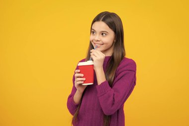 Teenage girl with take away cup of cappuccino coffee or tea. Child with takeaway cup on yellow background, morning drink beverage