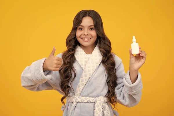 Tunny nose and allergy, nasal spray. Teen girl in pajama use nasal drops, stuffed nose isolated on yellow background